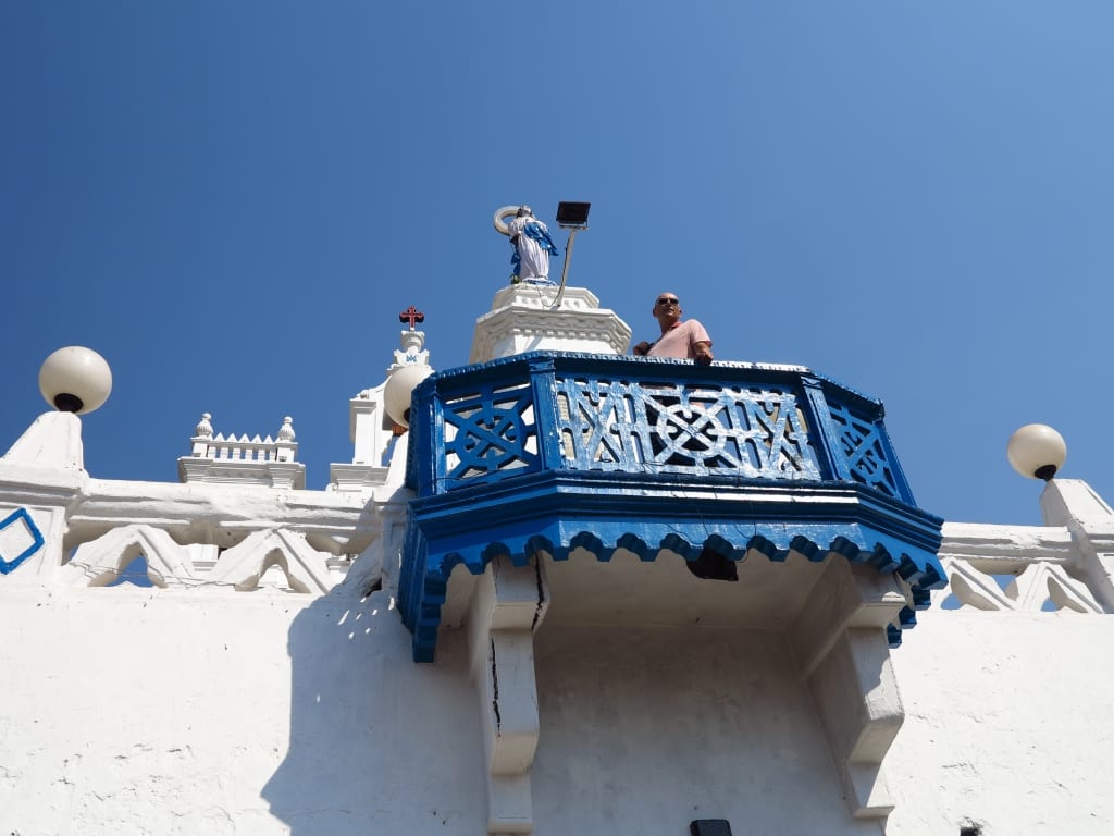 Mann steht auf Brüstung vor einer Kirche