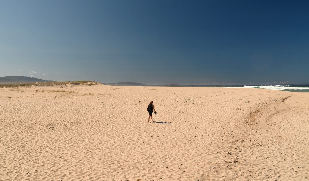 Frau läuft alleine über Sandstrand