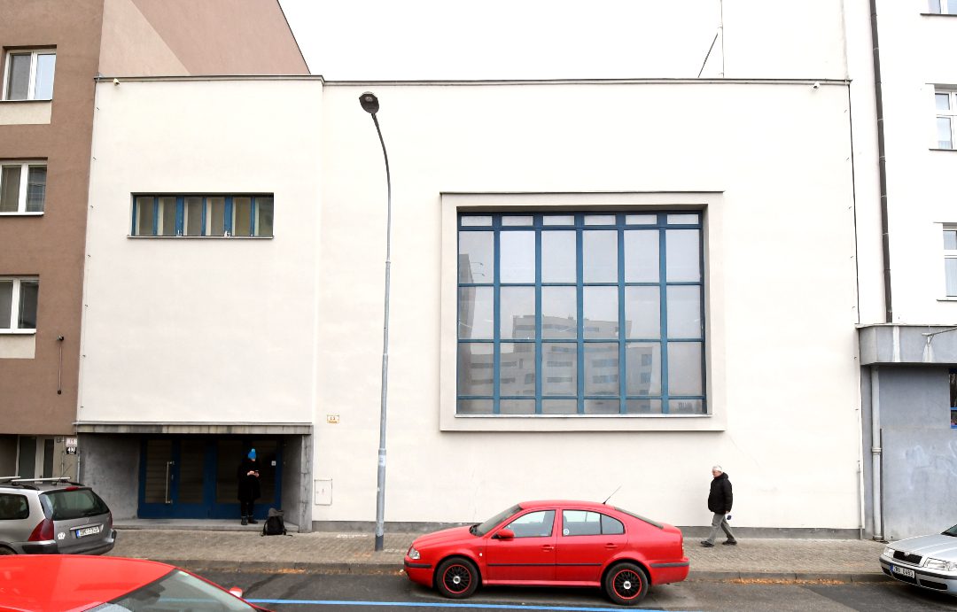 Rotes Auto vor weißem funktionalistischen Bau