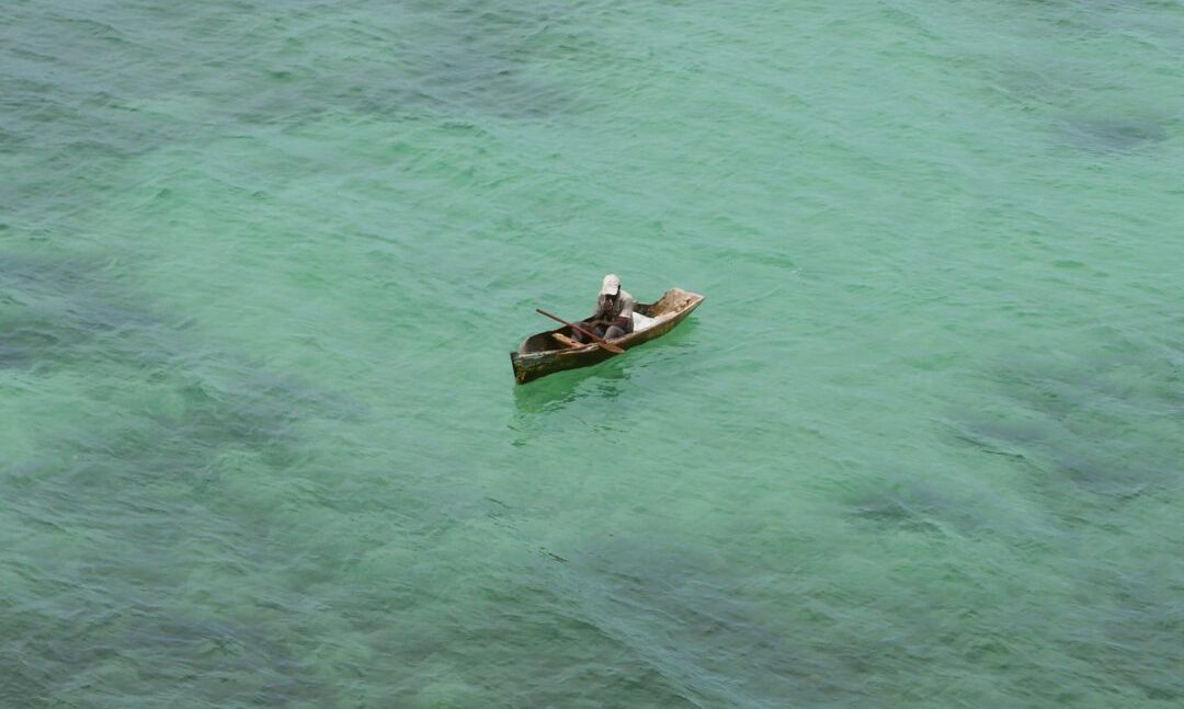 Mann im Einbaum im türkisfarbenen Wasser