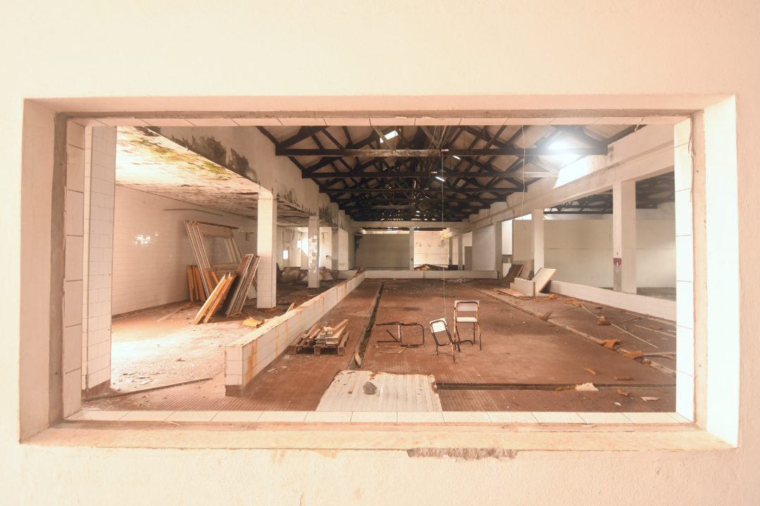 Blick durch ein Fenster in eine leer geräumte Fabrikhalle