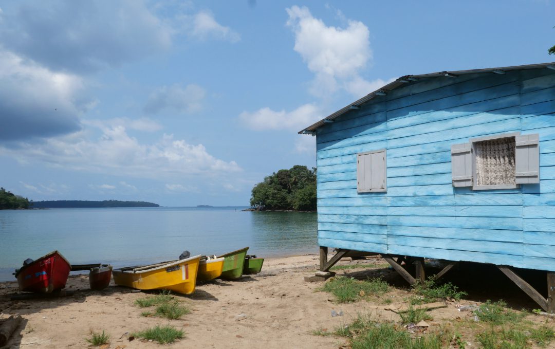 Blaues Holzhaus und bunte Boote an einem Strand