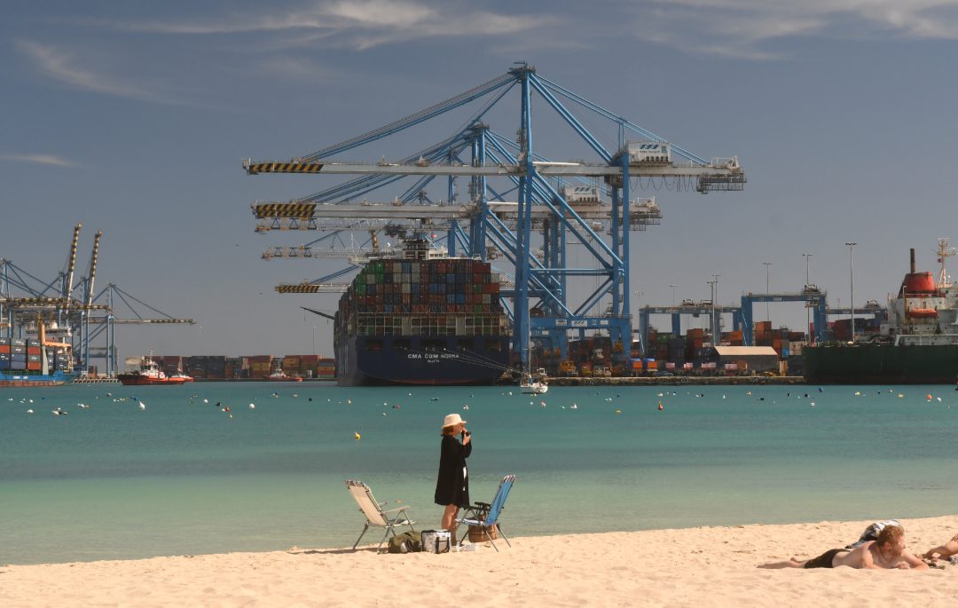Strand vor einem riesigen Containerhafen