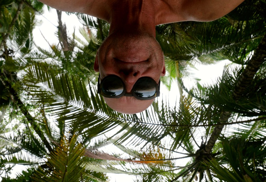 Mann macht Selfie unter Palmen