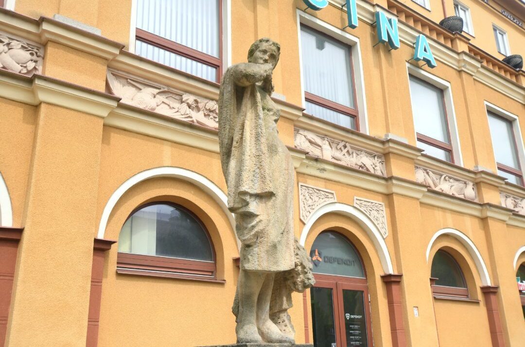 Sozialistische Skulptur vor gelbem Gebäude