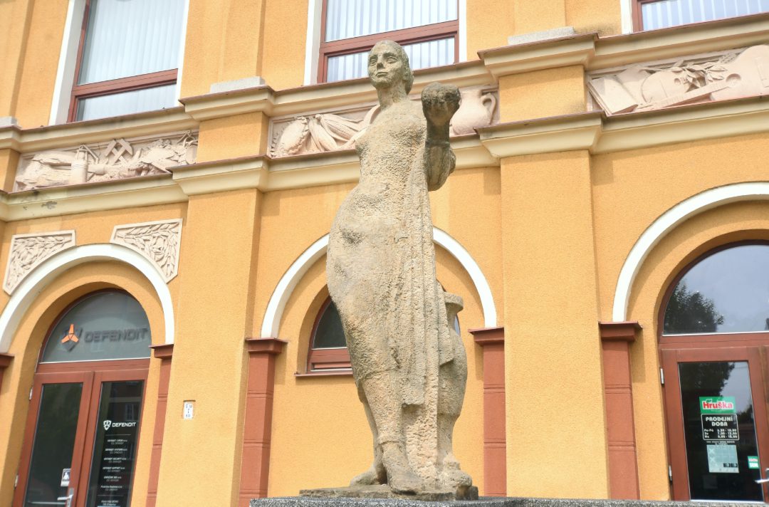 Sozialistische Skulptur vor gelbem Gebäude