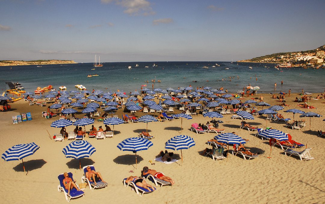Sandstrand mit blau-weißen Sonnenschirmen und Liegen
