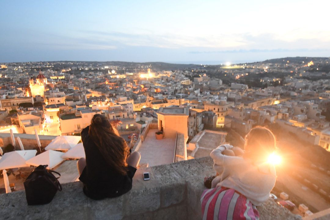 Frau blickt im Sonnenuntergang auf eine Stadt